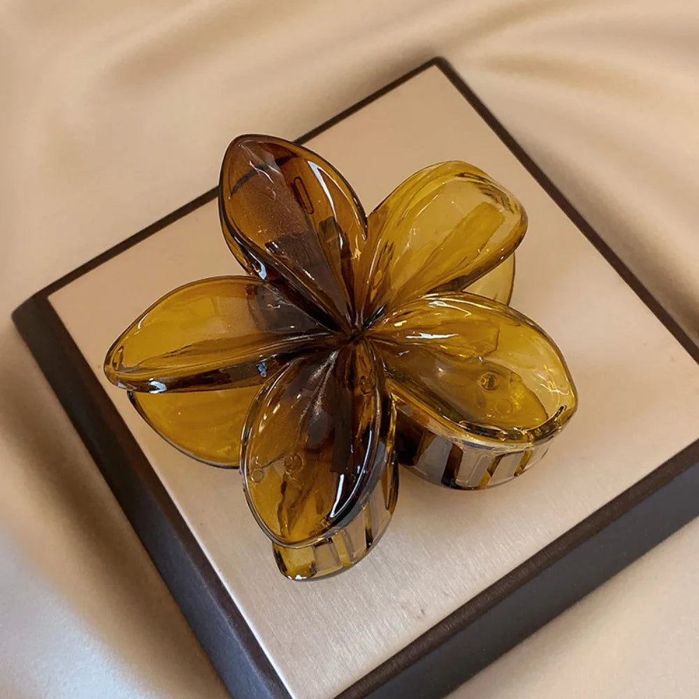 Black 8cm flower-shaped mermaid hair clip with glossy finish on beige display box – lightweight plastic fashion accessory for women.

