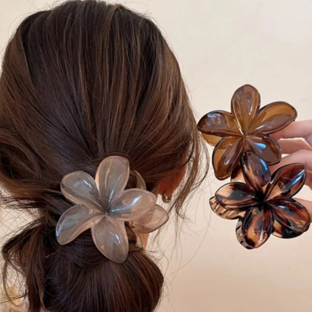 Black 8cm flower-shaped mermaid hair clip with glossy finish on beige display box – lightweight plastic fashion accessory for women.

