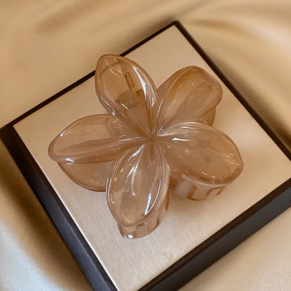 Black 8cm flower-shaped mermaid hair clip with glossy finish on beige display box – lightweight plastic fashion accessory for women.

