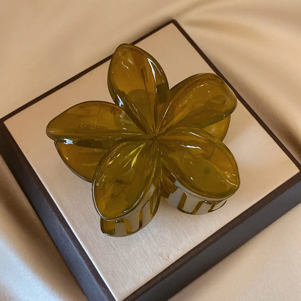 Black 8cm flower-shaped mermaid hair clip with glossy finish on beige display box – lightweight plastic fashion accessory for women.

